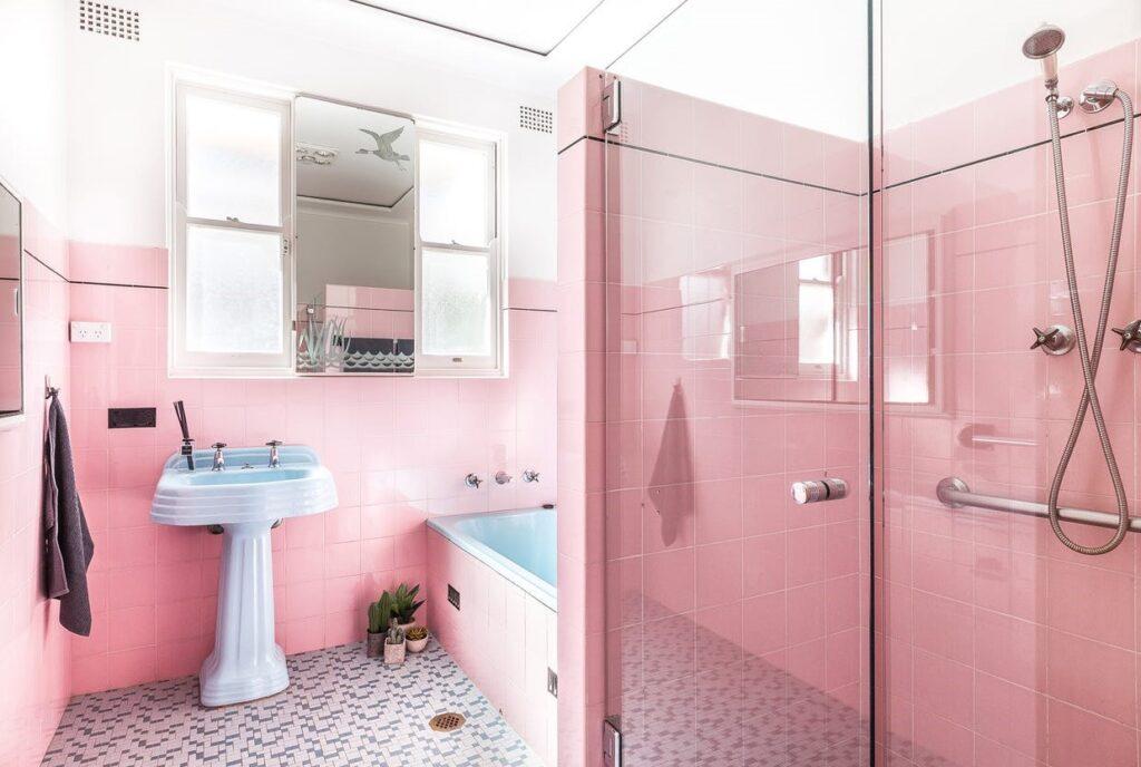 Pink wall tile, teamed with a blue enamel bath, blue porcelain pedestal basin and a matching blue toilet pan and porcelain cistern. 